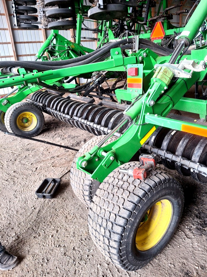 John Deere air seeder row units and disc openers inside a barn